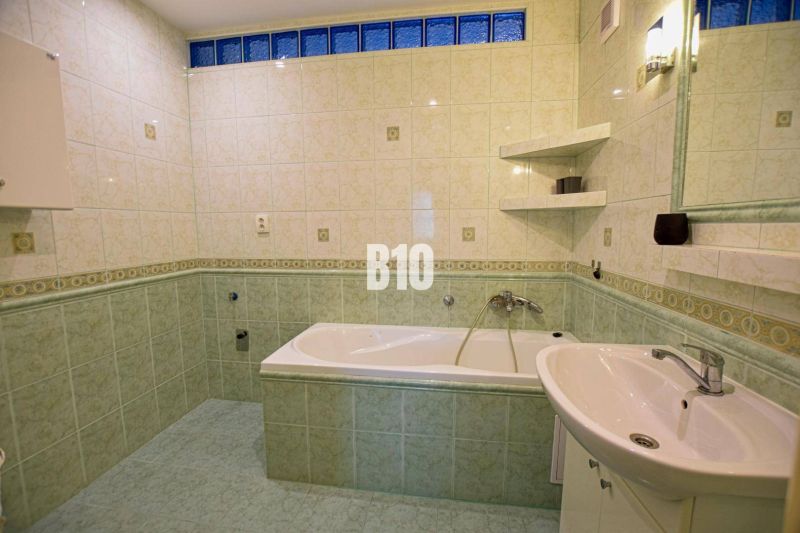 Fürdőszoba káddal és zöld csempékkel egy háromszobás lakásban.