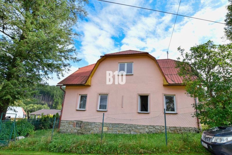 Családi ház Makovban, kőalappal és piros tetővel, zölddel körülvéve.