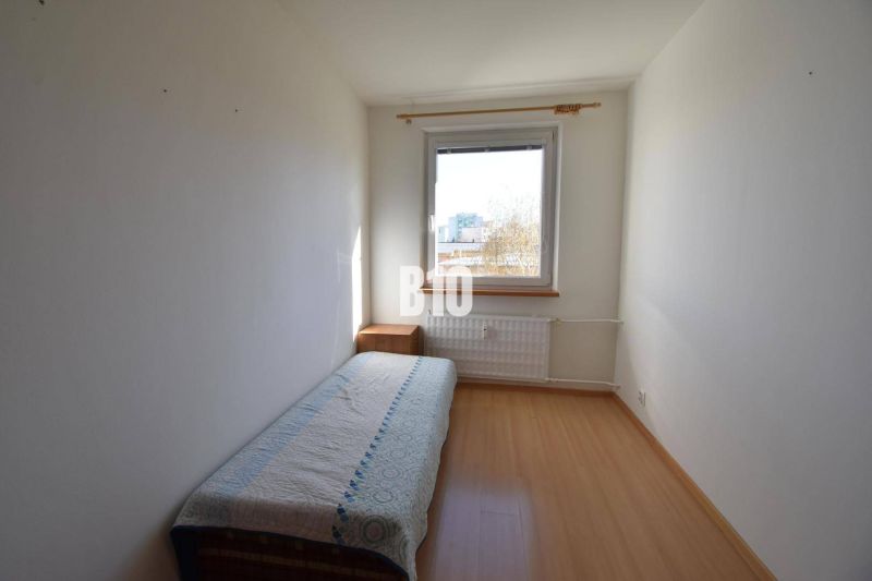 Egyágyas szoba, éjjeliszekrény és fa dekorációjú padló egy 5 vagy több szobás lakásban.