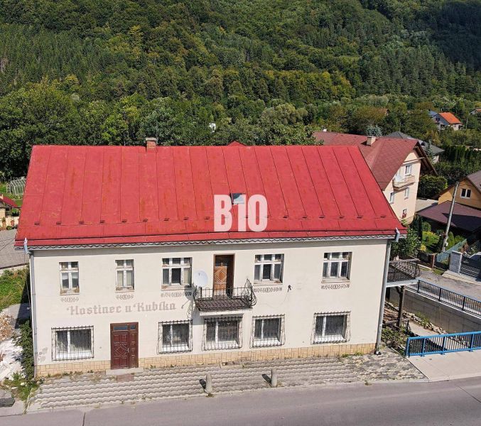 Egy épület Bélen piros tetővel, zölddel körülvéve és előtte úttal.