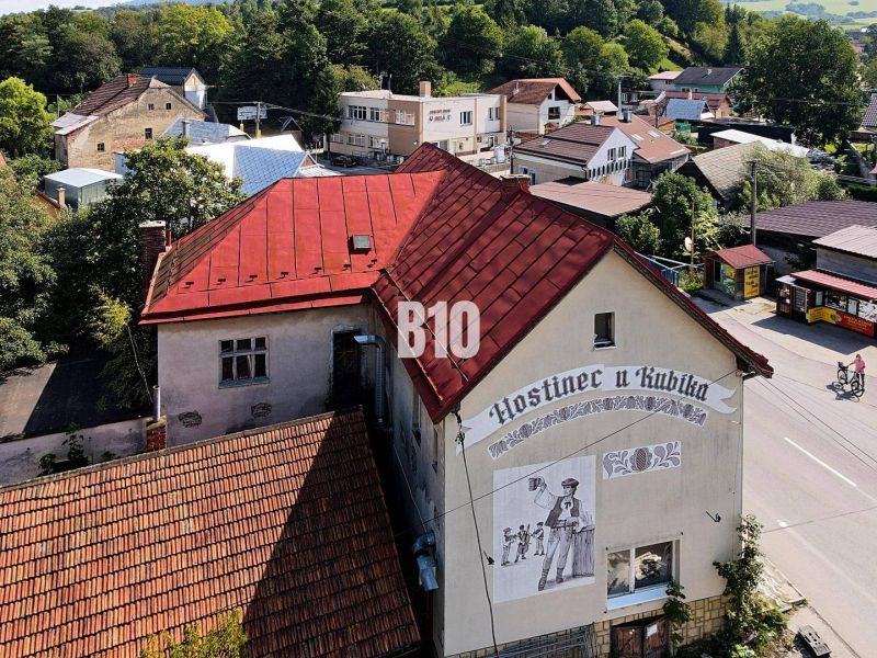Fogadó Bélán piros tetővel és egy sörös férfit ábrázoló falfestménnyel.