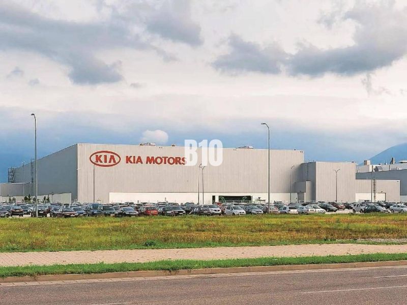 Kia Motors épülete Zsolnán, kereskedelmi telkek parkoló autókkal és füves területtel.