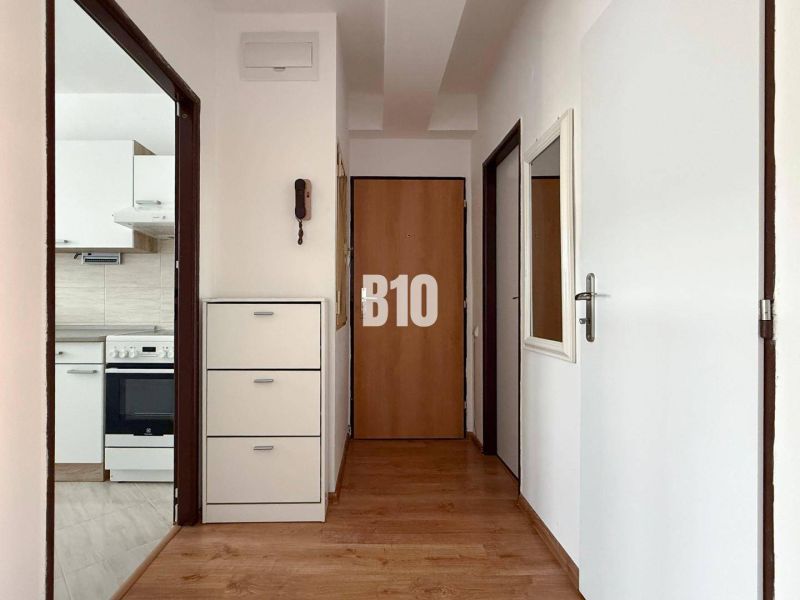 Folyosó fa dekorációs padlóval a Nyaraló apartmanban, a háttérben a konyha.