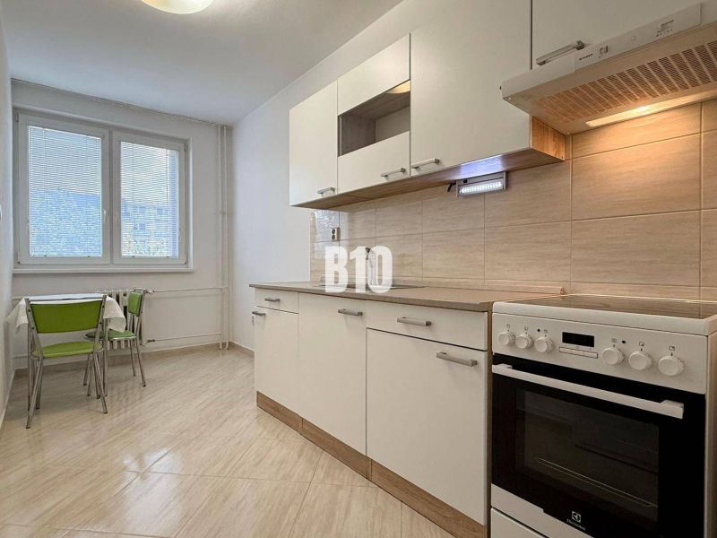 Világos konyha a Nyaraló apartmanban tűzhellyel és asztallal zöld székekkel.