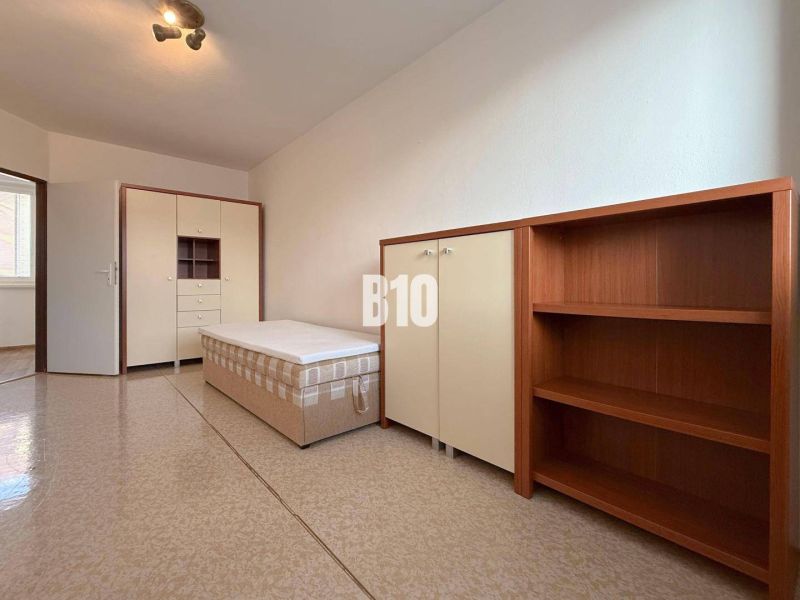 Világos szoba a Rekreációs apartmanban ággyal, szekrénnyel és polcrendszerrel.
