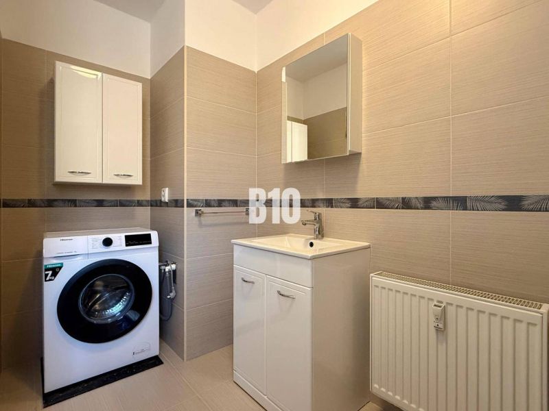 Fürdőszoba mosógéppel, mosdóval és szekrényekkel a Rekreačnom apartmanban.