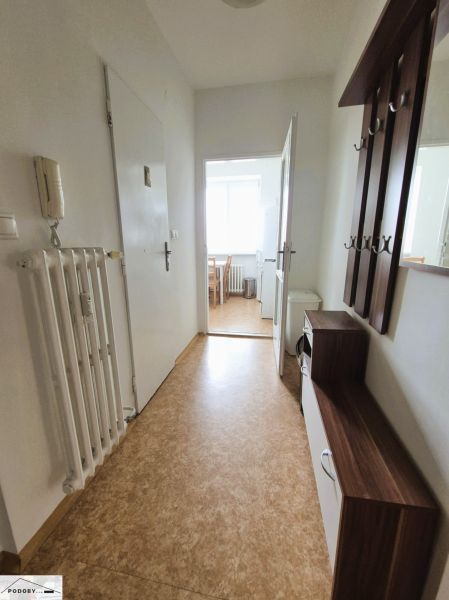 Háromszobás lakás folyosója fa dekor padlóval és bejárattal a konyhába.