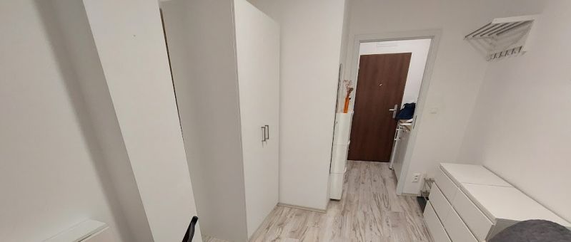 Hangulatos garzon fehér bútorokkal és fa mintázatú padlóval.
