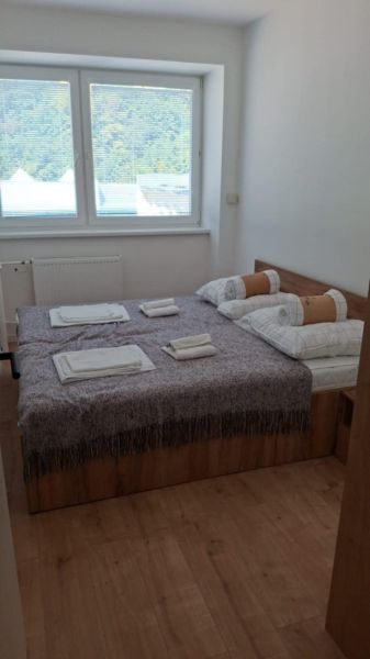 Hálószoba ággyal és ablakkal, fa dekoros padlóval egy kétszobás lakásban.