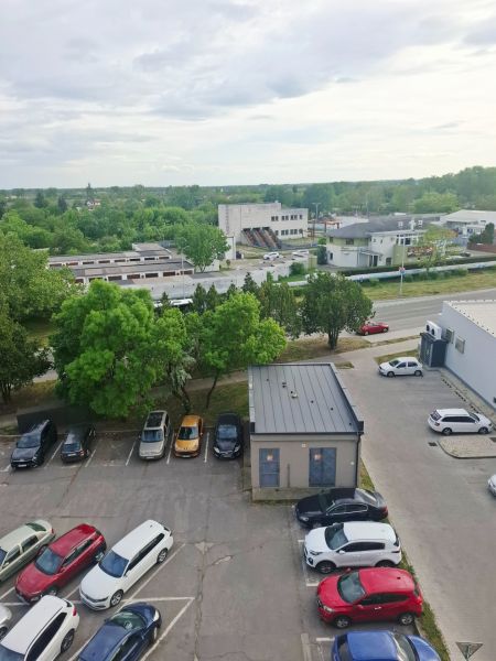 Parkoló autókkal, zöldterülettel és épületekkel Érsekújváron, a Nábrežná utcában.