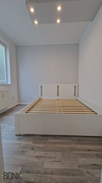 Franciaágy szobában, fa dekor padlóval és mennyezeti világítással.