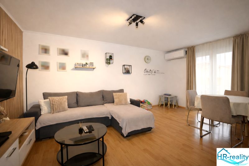 Kényelmes nappali tér egy üdülő apartmanban fa dekorációjú padlóval és étkezőasztallal.