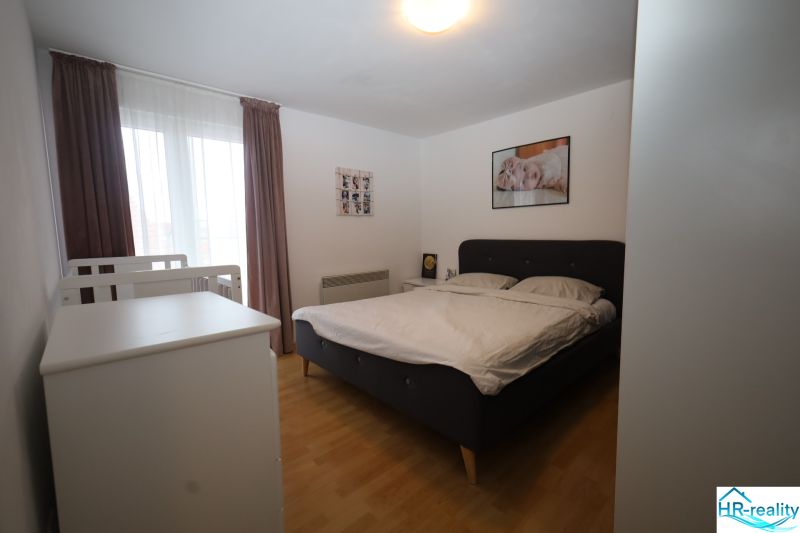 Hálószoba ággyal és gyermekággyal a nyaraló apartmanban, fa dekor padlóval.