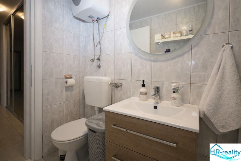 Fürdőszoba a nyaraló apartmanban mosdóval, tükörrel és WC-vel.