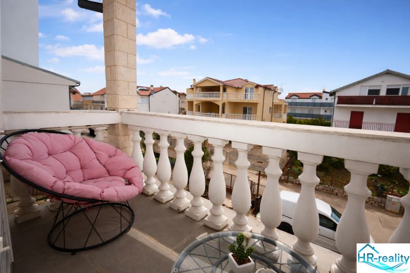 A vodicei nyaraló apartman erkélye, kényelmes szék kilátással a beépített területre.