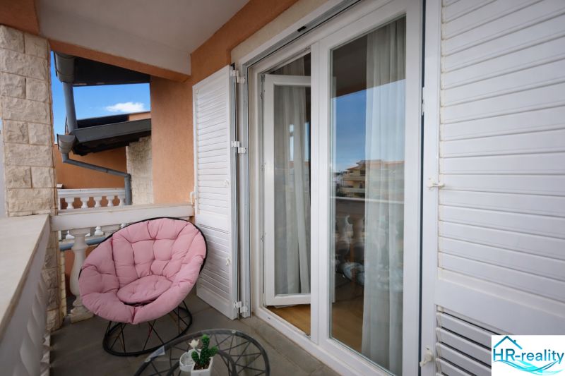 Rekreációs apartman erkélye kényelmes székkel és kilátással Vodicére.