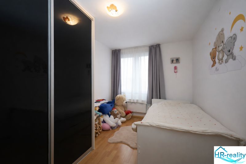 Gyerekszoba a Nyaraló apartmanban játékokkal, ággyal és fa dekorációjú padlóval.