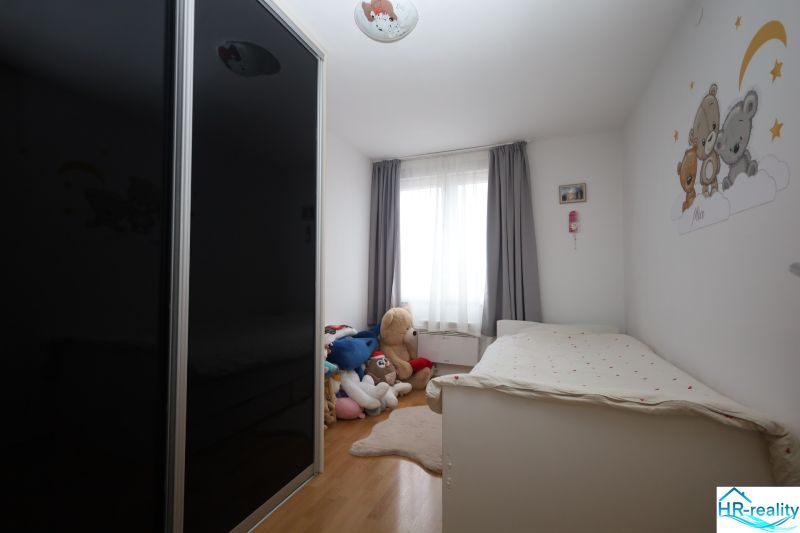 Gyerekszoba a Nyaraló apartmanban ággyal, szekrénnyel és plüss játékokkal a padlón, fa dekorációval.