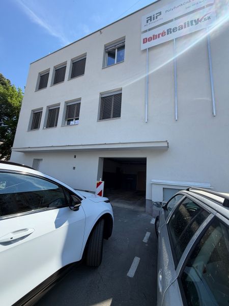 Épület garázsokkal a Prievidza, Hosszú utca 3 alatt, parkoló autók az épület előtt.