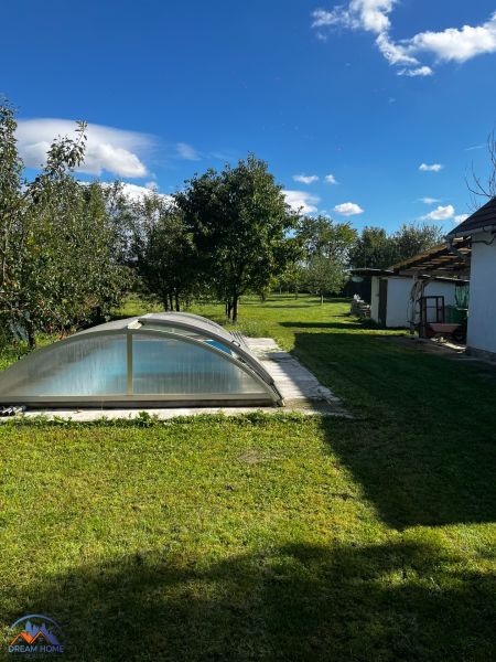 Családi ház a Csallóközi kertben, medencével íves fedél alatt és füves területtel.