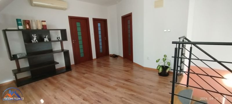 Családi ház belső tere fa dekorációs padlóval, polccal és növénnyel.