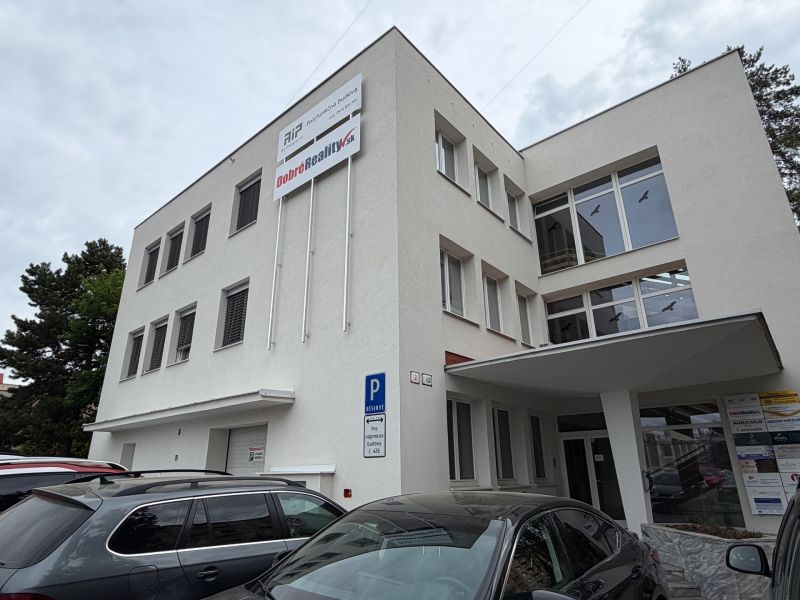 Irodaház a Prievidza Dlhá utcáján parkoló autókkal.