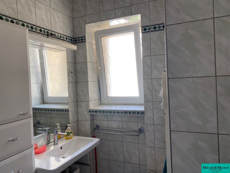 Fürdőszoba egy kétszobás lakásban csempékkel, mosdóval és ablakkal.