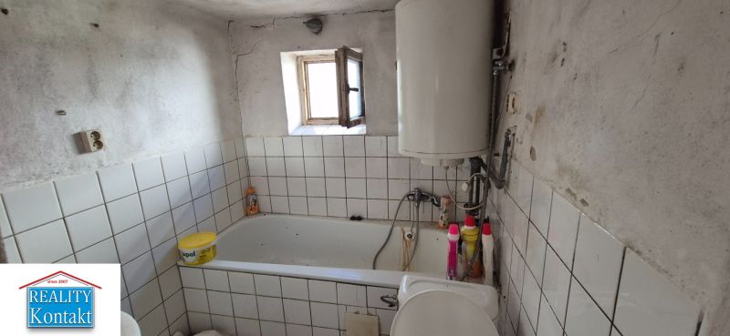 Fürdőszoba családi házban csempékkel, káddal és bojlerrel.