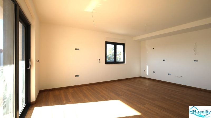 Tágas szoba nagy ablakkal és fa dekorációjú padlóval az üdülő apartmanban.