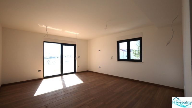 Nyaraló apartman belső tér nagy ablakokkal és fa dekorációjú padlóval.