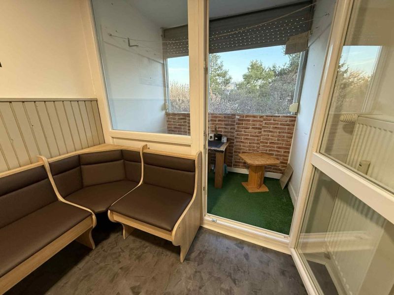 Világos loggia egy 4 szobás lakásban kilátással és fa bútorokkal.