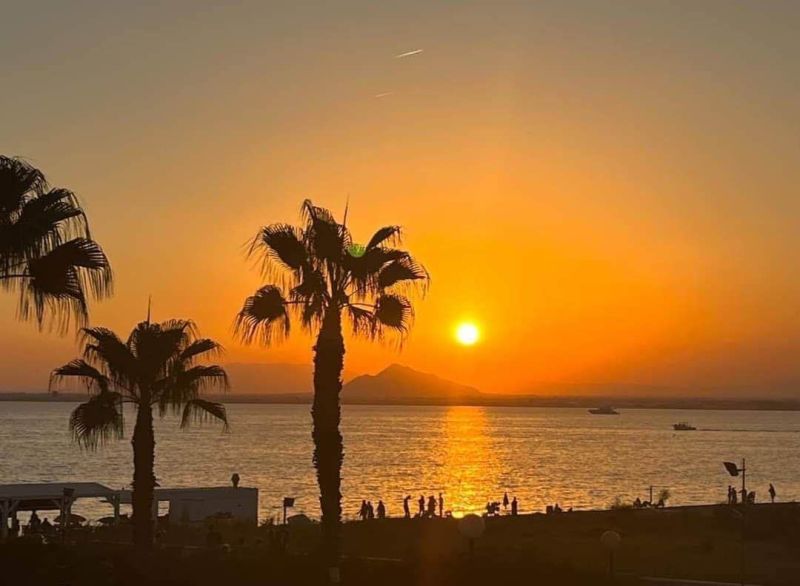 Naplemente pálmafákkal és tengerrel La Manga del Mar Menorban, Spanyolország.