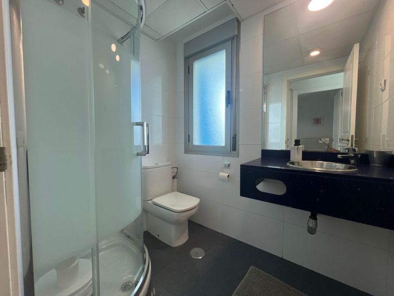 Fürdőszoba WC-vel, zuhanyzóval és mosdóval egy üdülő apartmanban.