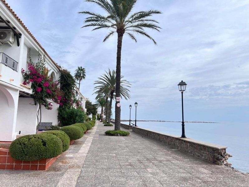 Tengerparti sétány La Manga del Mar Menorban, Spanyolország, pálmafákkal és lámpákkal szegélyezve.