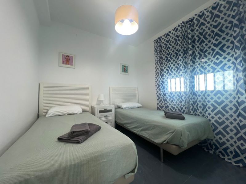 Rekreációs apartman két egyszemélyes ággyal, mintás függönyökkel és asztallal lámpával.