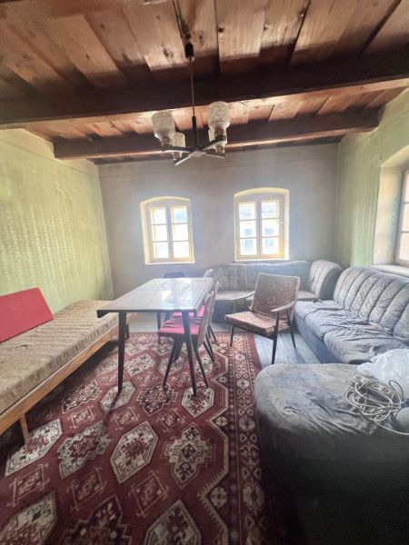 Nappali egy családi házban, fa mennyezettel, kanapéval és mintás szőnyeggel.