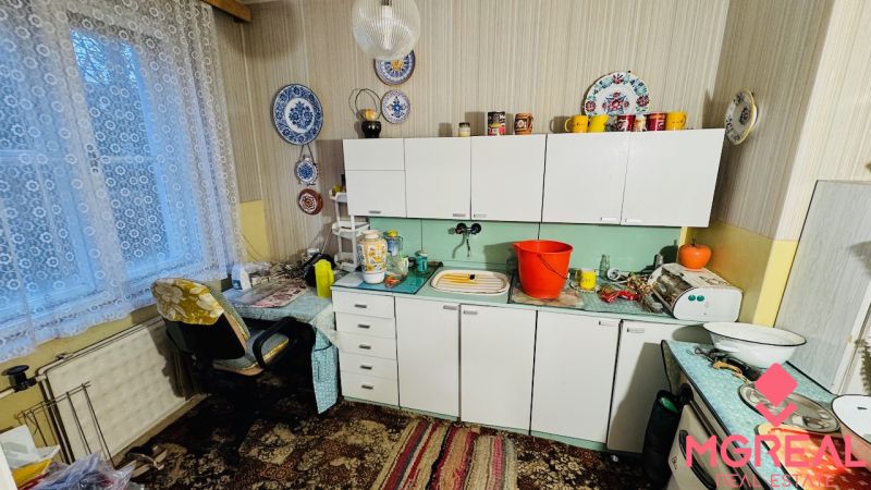 Konyha egy háromszobás lakásban függönyökkel, csipkés dekorációkkal és antik bútorokkal.