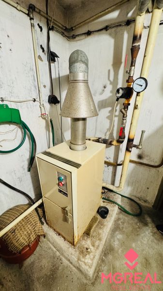 Fűtés a háromszobás lakás technikai helyiségében, falakon vezetékekkel és csövekkel.