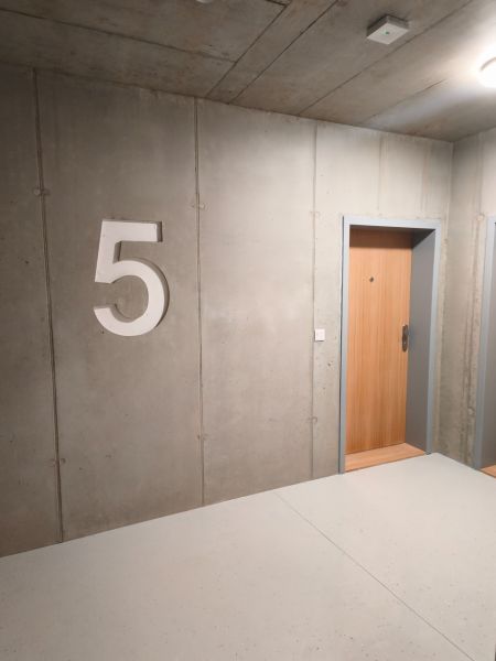Betonfal ötös számmal és faajtóval egy kétszobás lakásban.