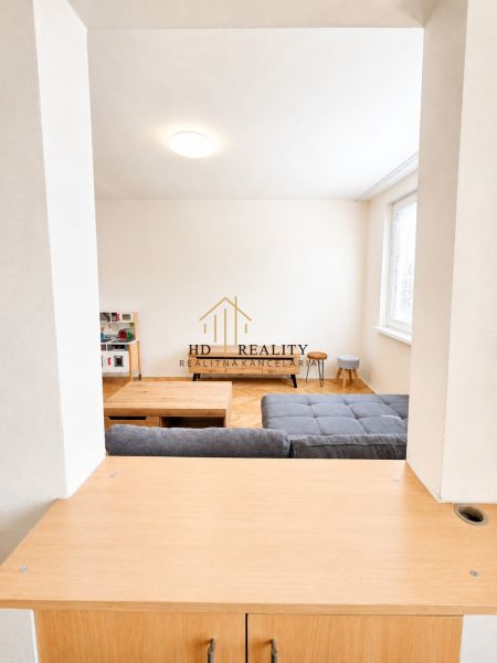 Nappali egy kétszobás lakásban világos bútorokkal és fa dekorációjú padlóval.