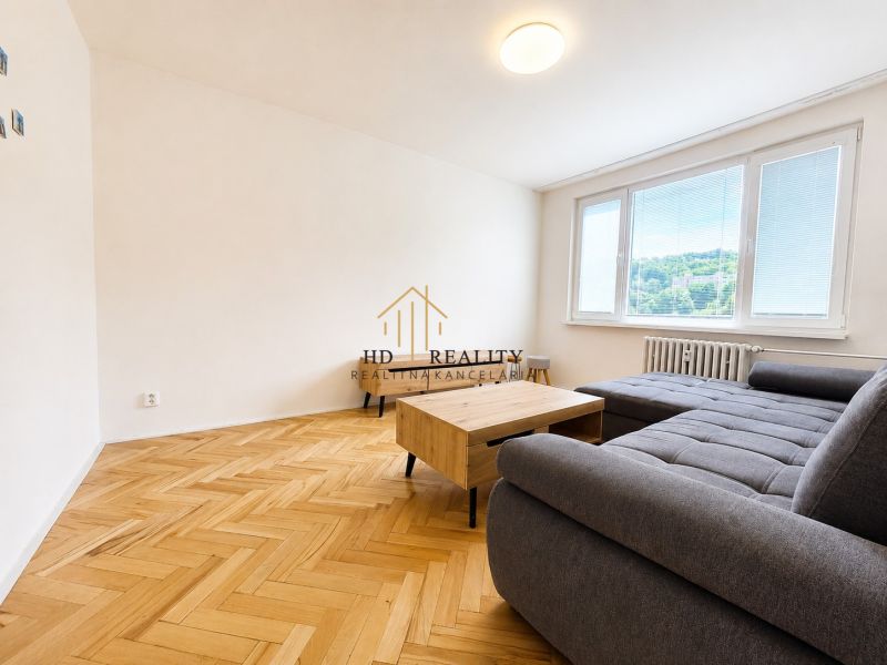Nappali egy kétszobás lakásban kanapéval és fa dekorációjú padlóval.