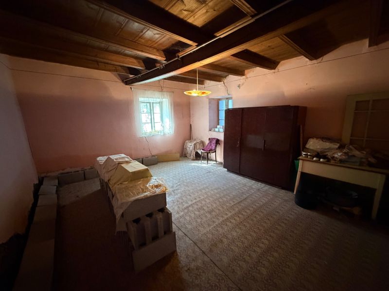 Szoba egy családi házban bútorokkal, téglakupacokkal és fa mennyezettel.