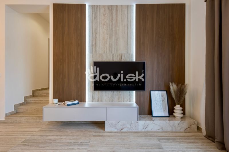 Családi ház belső tere fa dekorációval ellátott fallal, televízióval és dekorációkkal.