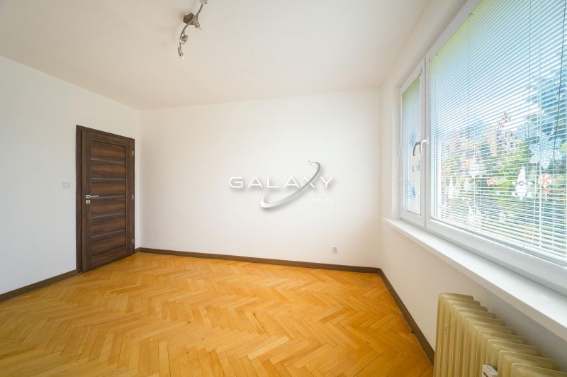 Szoba egy háromszobás lakásban fa dekorációjú padlóval és nagy ablakokkal.