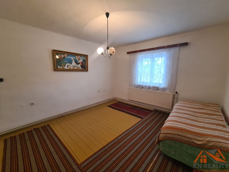 Családi ház belső tere ággyal, képpel és függönyös ablakkal.