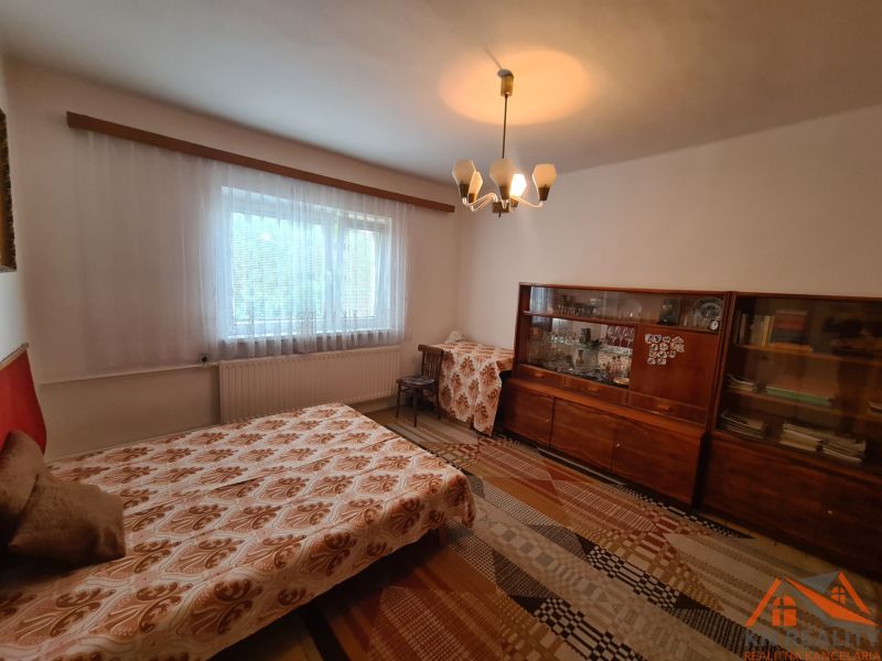 Szoba kihúzható kanapéval, régi vitrinnel és függönnyel, családi házban.