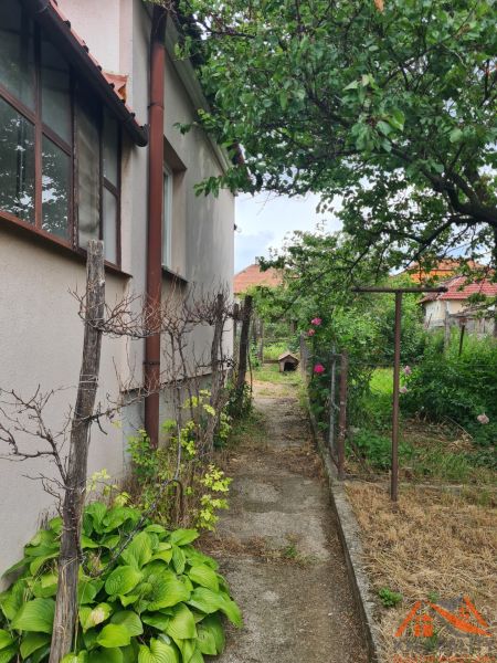 A családi ház melletti kert Dulovcén, járdával és növényekkel.
