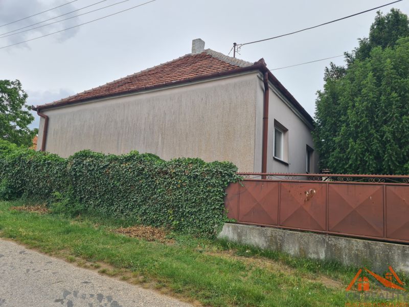 Családi ház Dulovce-ban, zölddel benőtt kerítéssel, az út mellett elhelyezkedve.