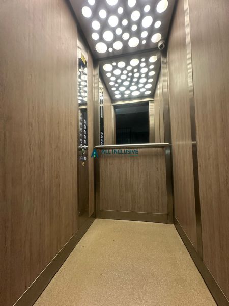 A lift belső tere egy kétszobás lakásban, fa dekorációval a falakon.