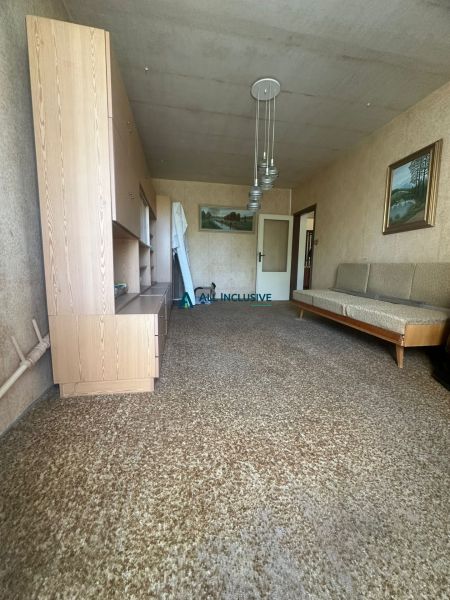 Nappali egy kétszobás lakásban szőnyeggel és fa bútorokkal.